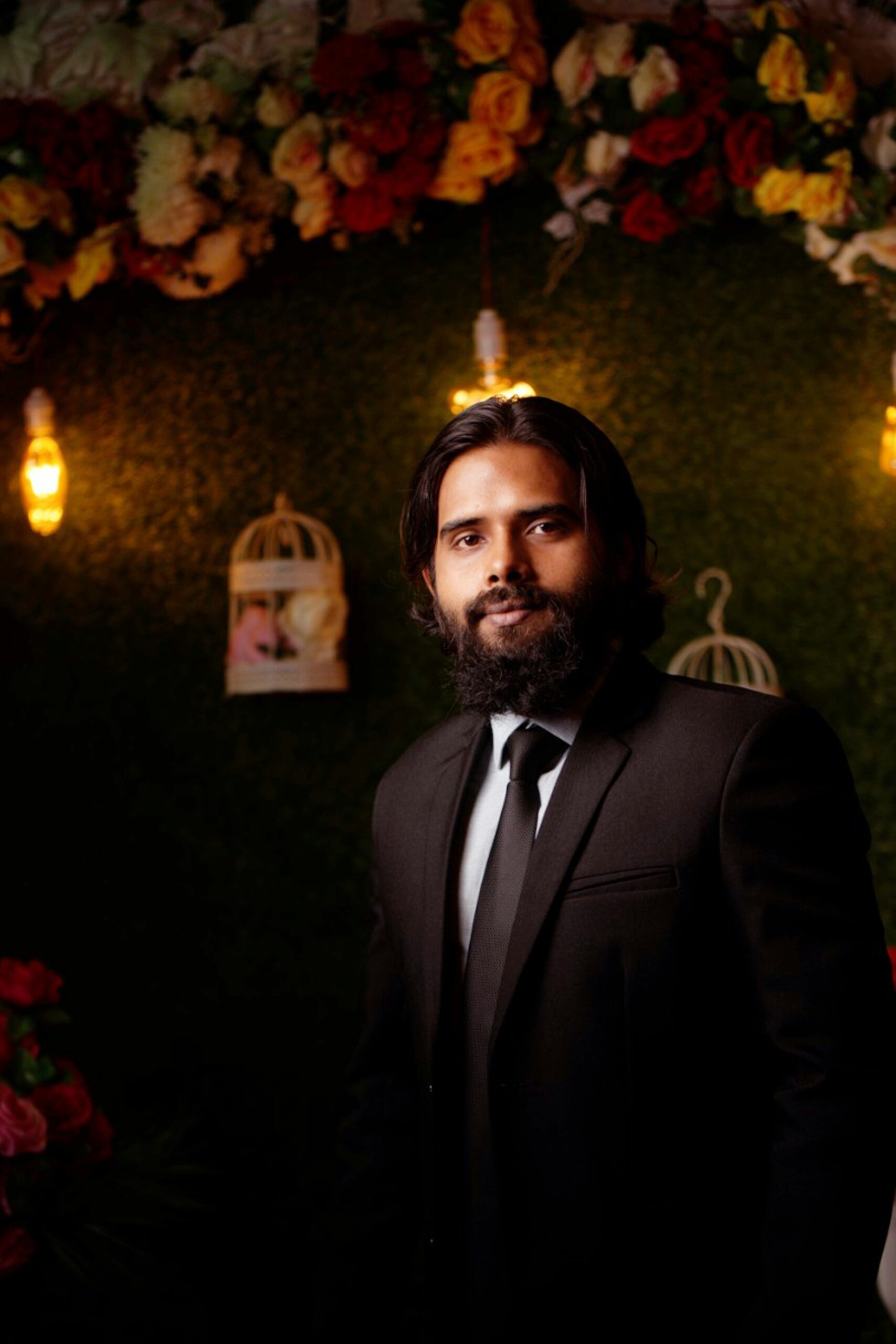 a man in a suit standing in front of a floral wall